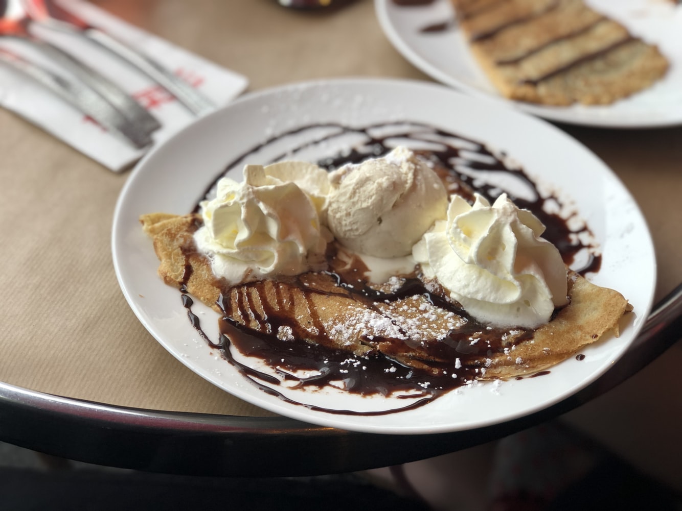 A folded pancake with ice cream and chocolate sauce