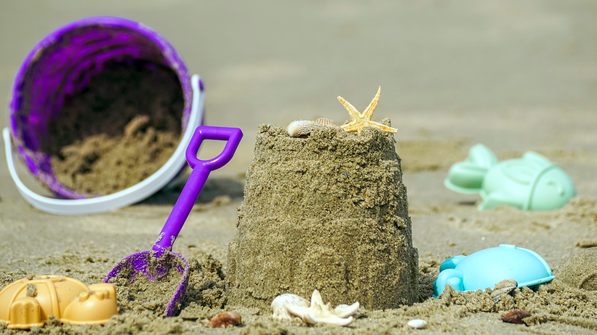 A sandcastle with a bucket, spade and some seashells