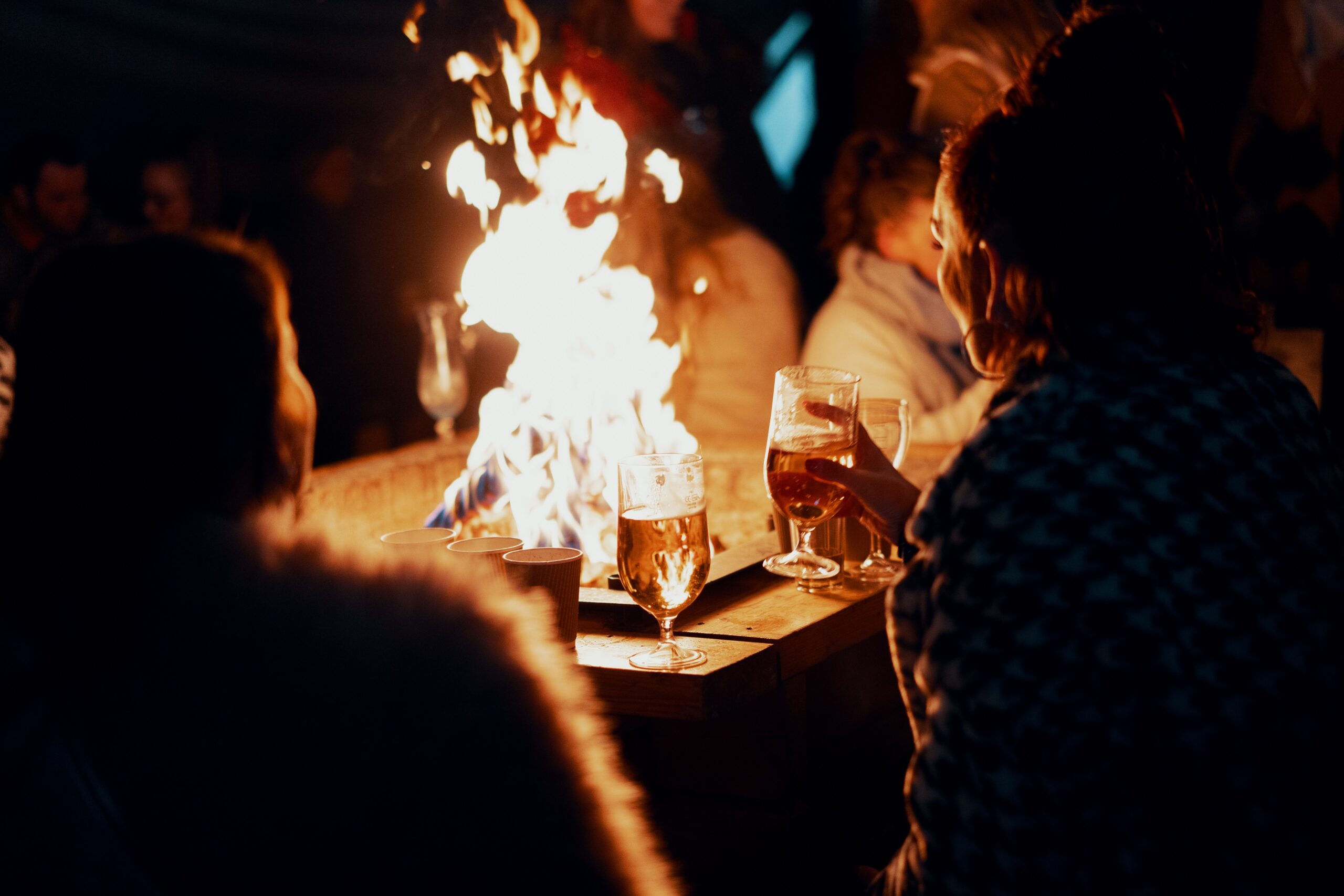 a group of friends having a drink around a fire outside