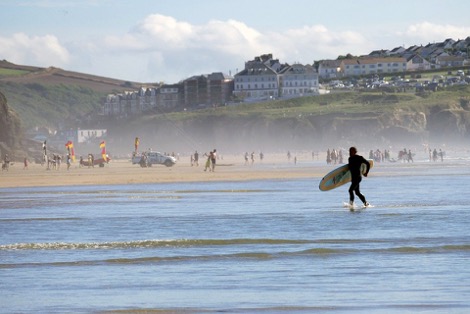 A person with a surfboard running along the coast at St. Ives in Cornwall