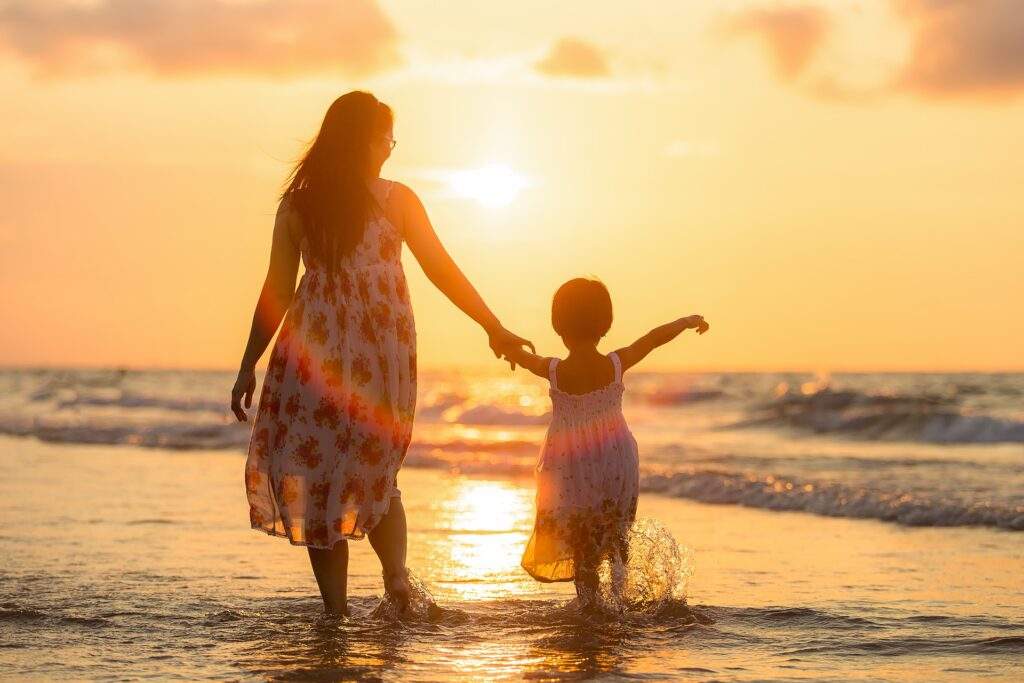 Mother and daughter playing in the sea at sunset