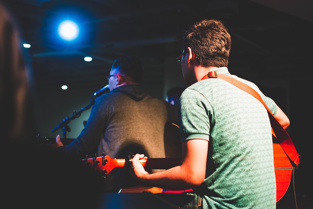 Two men with acoustic guitars performing on stage