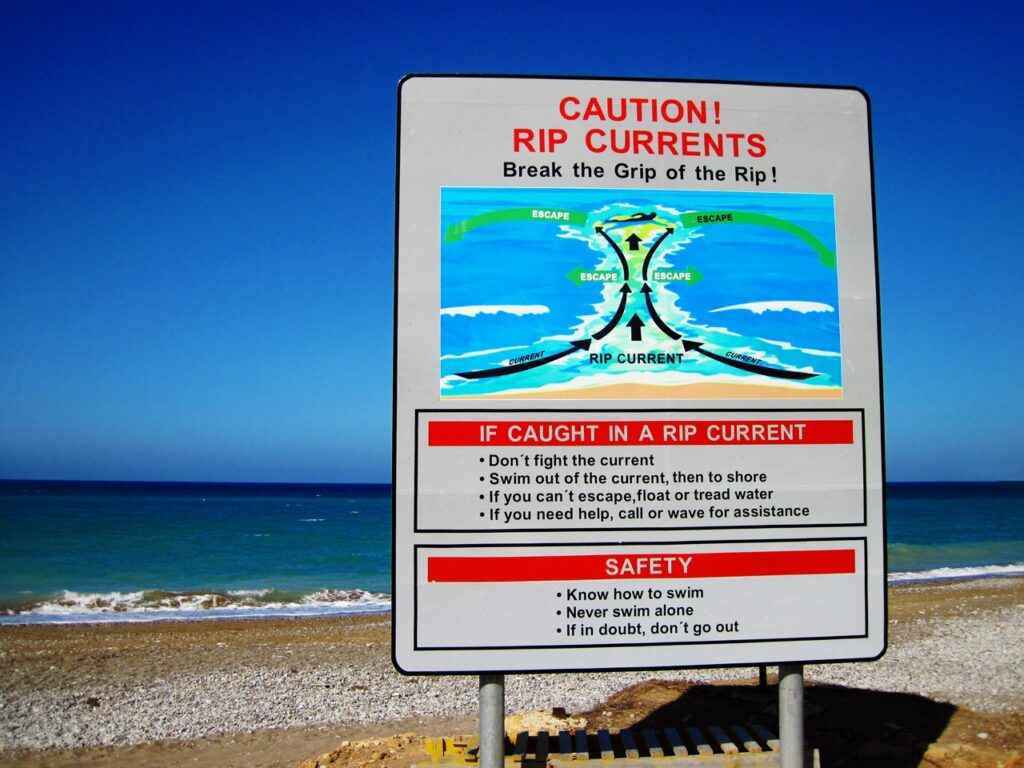 sign on a beach warning of rip currents