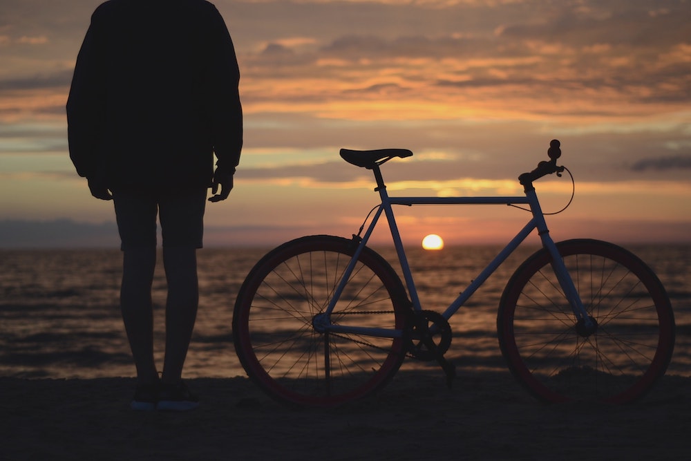 A man stood next to his bike looking at the beach